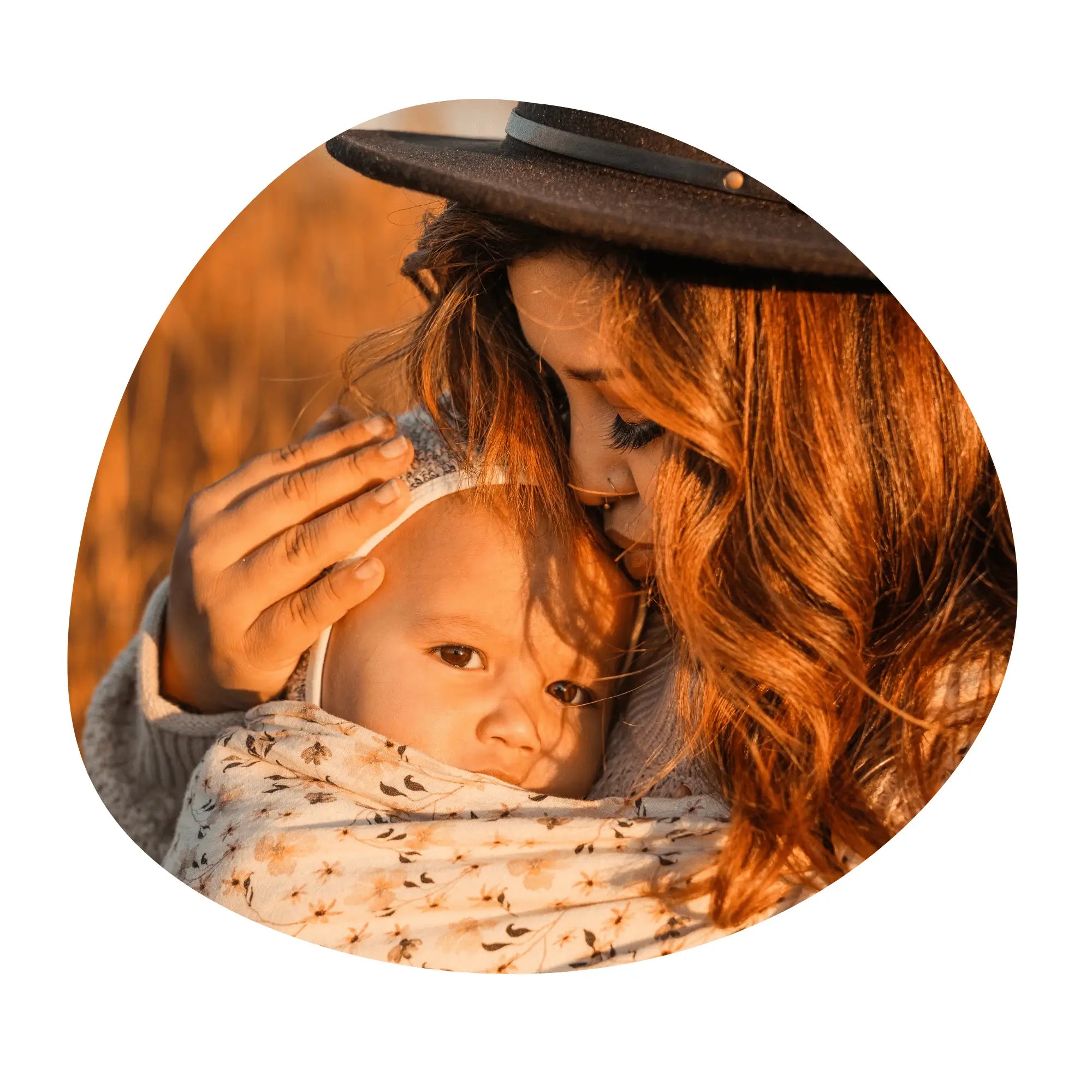 A woman kisses her baby worn in a floral ring sling