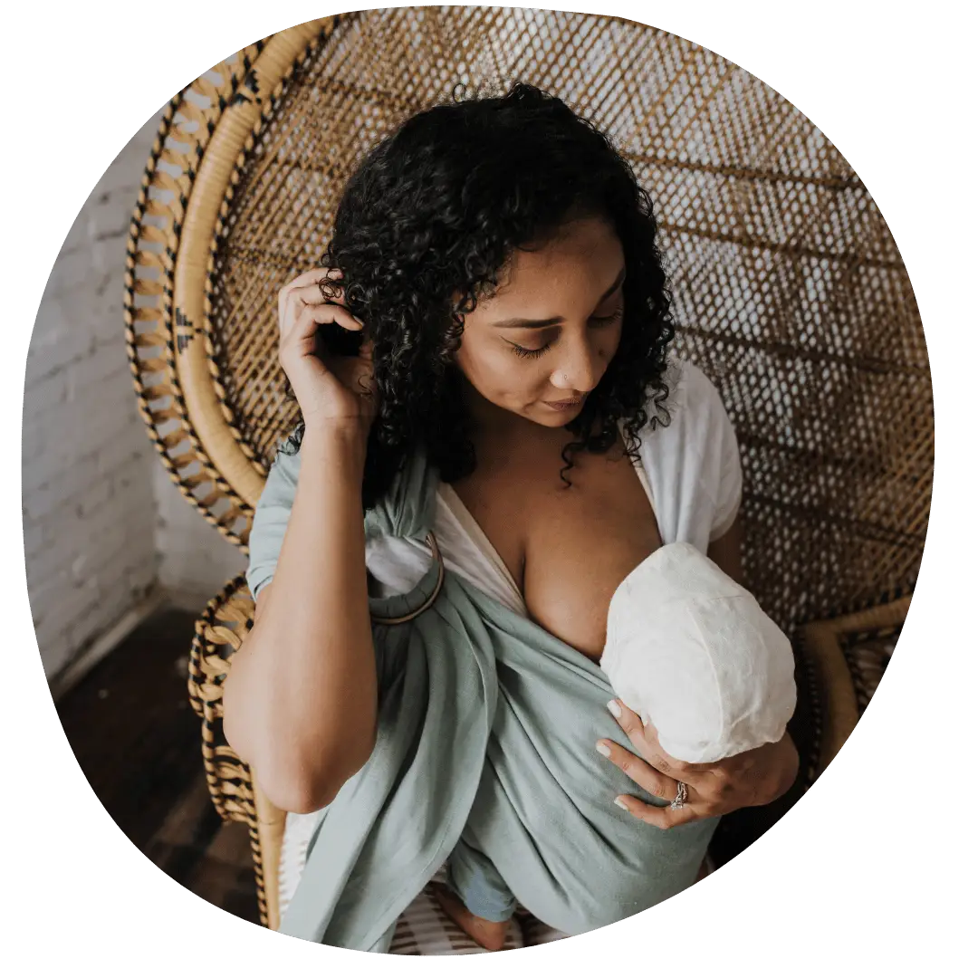 a black woman nursing her baby in a hope&plum baby carrier