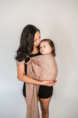 Mother holding baby in a ring sling.