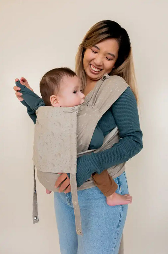 Baby in a beige wrap carrier.