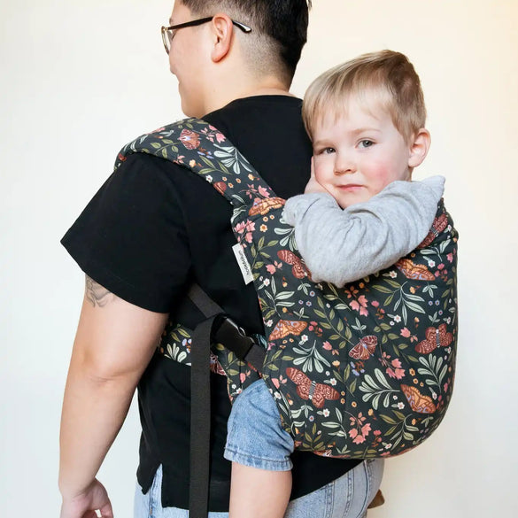 Floral baby carrier with child.
