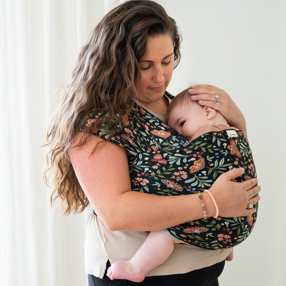 Mother holding baby in black moth print baby wrap carrier