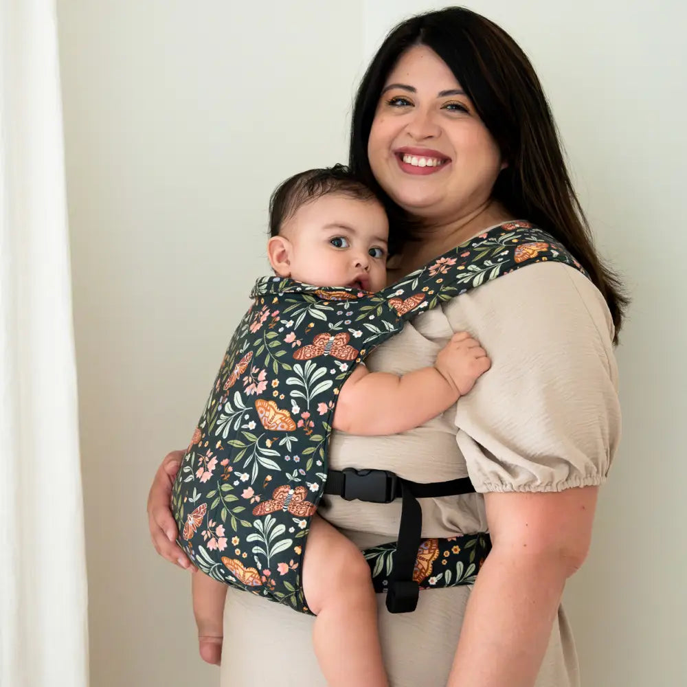 Mother wearing her baby in a lark baby carrier in moth print 