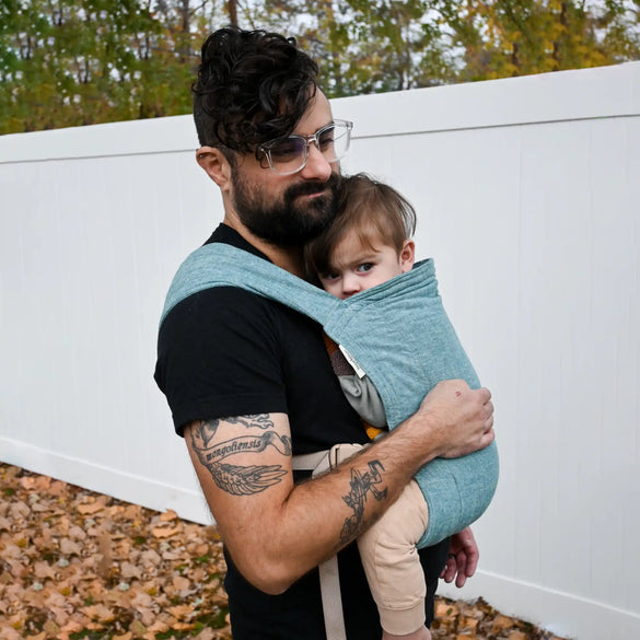 Man carrying baby in sling.