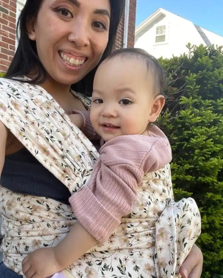 Mother carrying baby in floral sling.