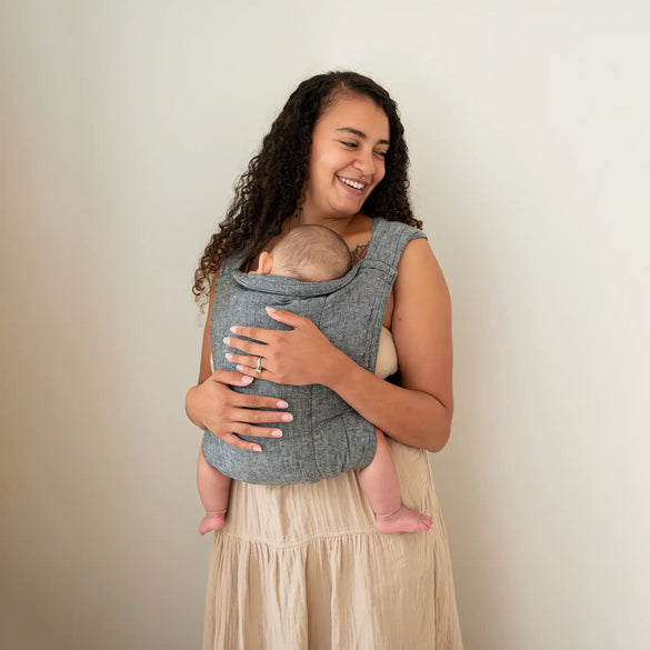 Mother carrying baby in gray sling.