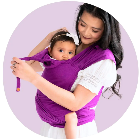 An Asian mother smiling and babywearing her toddler in a purple meh dai carrier 