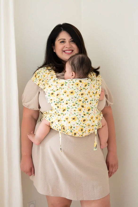 Woman wearing a baby carrier with a sunflower pattern.