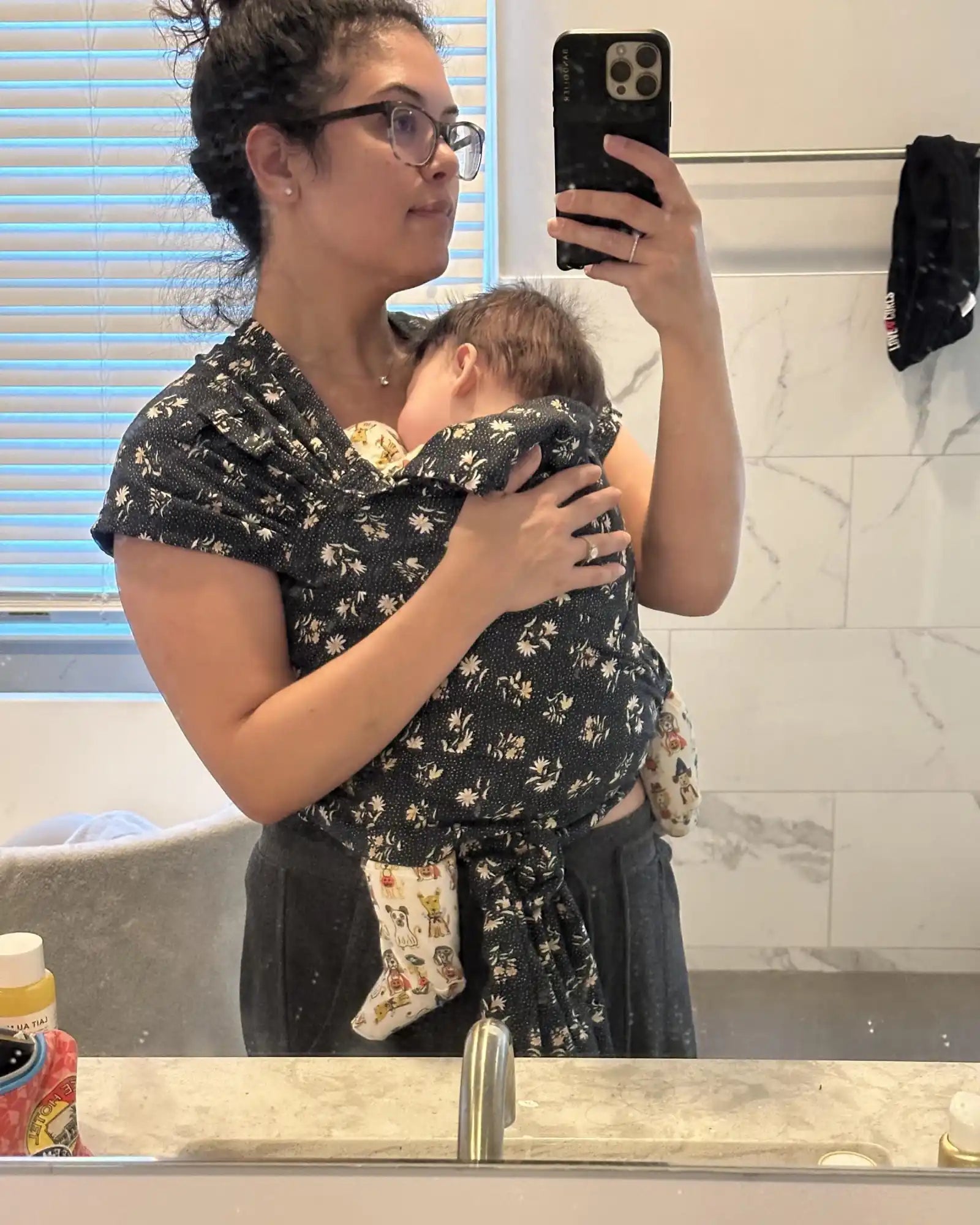 Woman holding baby in floral wrap.