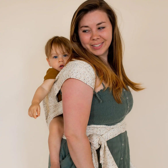 Woman carrying baby in floral wrap.