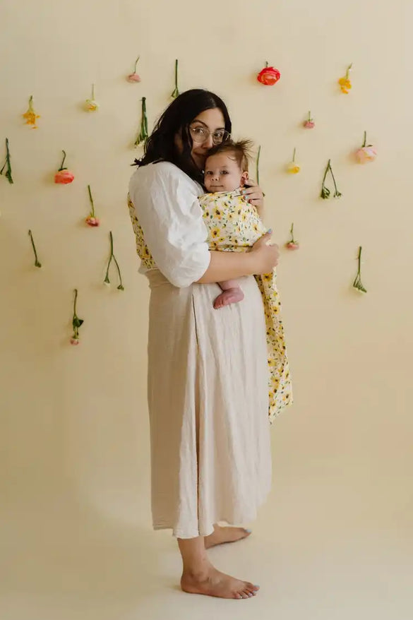 Latina mother holding baby boy in a sunflower ring sling in a short length.