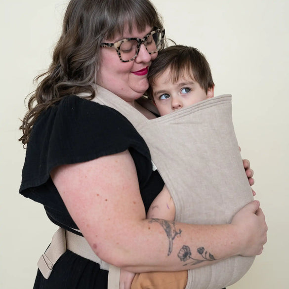 Woman carrying child in sling.